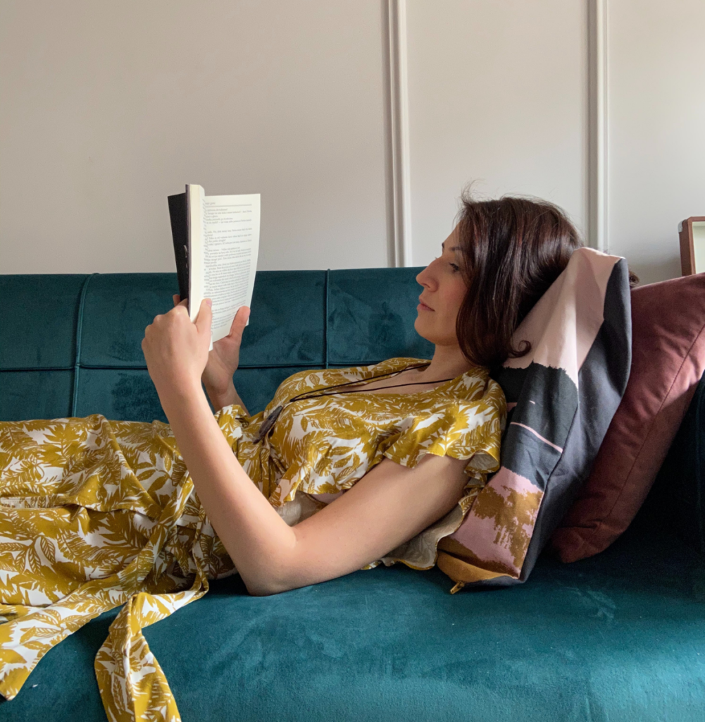 Anna Kovach astrologer laying in her living room and reading book